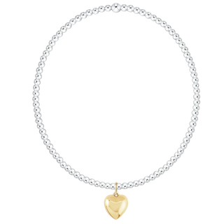 A silver beaded necklace with a polished yellow gold heart-shaped pendant, displayed on a clean white background.