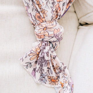 Floral patterned swaddle blanket draped over a beige surface
