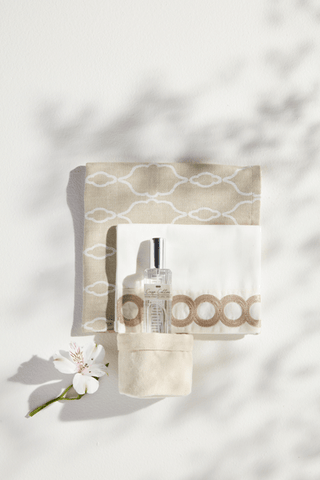 Spray bottle and pouch on a towel surface with a floral element