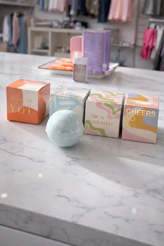 Bath bombs and boxes on a marble countertop with a store interior in the background