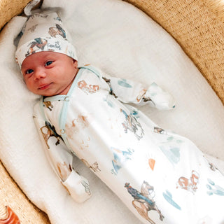 Newborn baby in a crib wearing a patterned outfit and hat.
