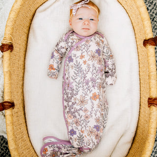 Baby in a floral swaddle blanket lying in a moses basket.