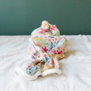Floral-patterned baby outfit on a white surface with a green background