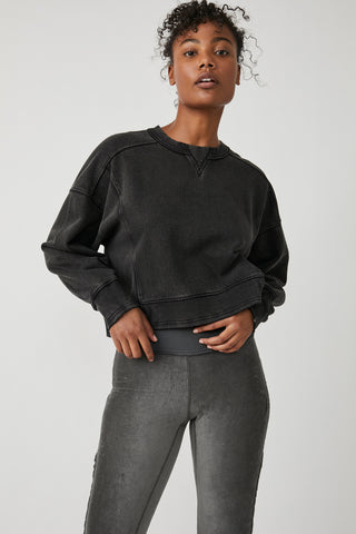 Person wearing a black sweatshirt and gray pants on a white background