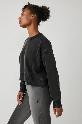 Person wearing a black sweatshirt and gray pants on a light gray background