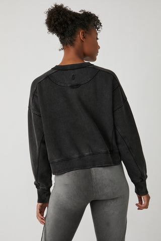Person wearing a black hoodie and gray leggings on a white background
