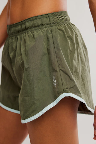 Green athletic shorts with a brand logo on a plain background
