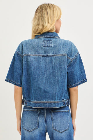 Person wearing a blue denim jacket and pants on a white background