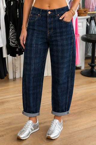 Woman wearing dark wash plaid jeans and silver sneakers in a boutique