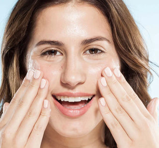 Woman applying cream to her face with a clear background