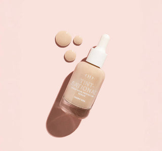 Skincare serum bottle with applicator on a pink background