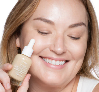Woman applying a skincare product to her face with a dropper bottle.