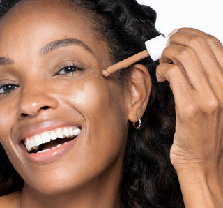 Woman applying makeup with a dropper to her face