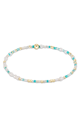 Beaded bracelet with turquoise, gold, and white beads on a white background