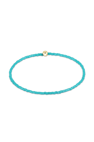 Turquoise beaded bracelet with a gold clasp on a white background