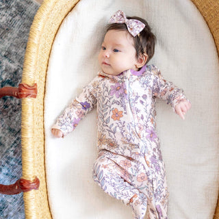 Baby in a floral outfit lying in a moses basket