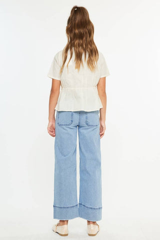 Person wearing a white top and light blue jeans on a white background