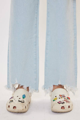 White clogs with colorful designs worn indoors against a light blue curtain.