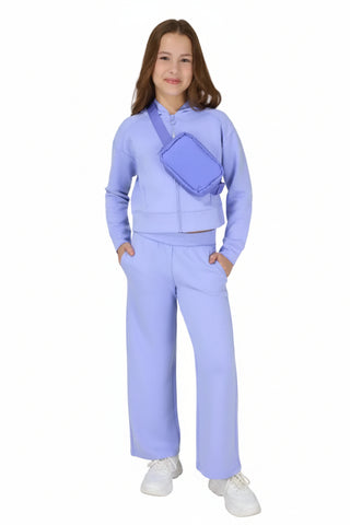 Person wearing a lavender outfit with a matching bag on a white background