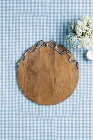 Wooden cutting board with metal handles on a blue checkered tablecloth