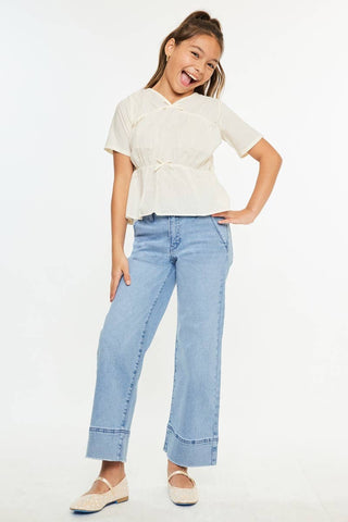 Young girl wearing a white top and blue jeans on a white background
