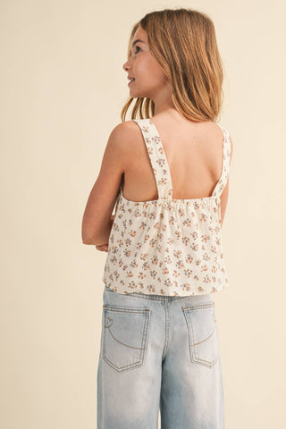 Child wearing a floral top and light blue jeans on a beige background