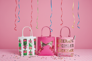 Three pink gift bags with decorative designs on a striped background