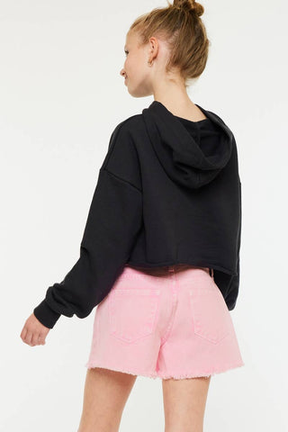 Person wearing a black hoodie and pink shorts on a white background