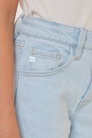 Light blue jeans with a brand label on the pocket against a neutral background