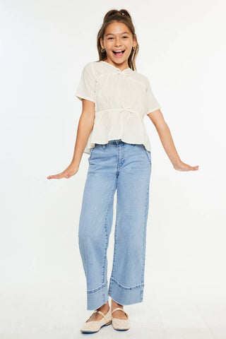 Young girl wearing a white blouse and light blue jeans on a white background