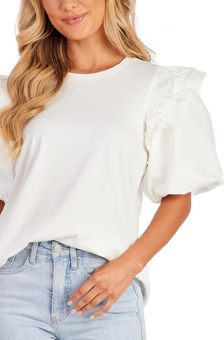 Woman wearing a white blouse with ruffled sleeves and light blue jeans on a white background