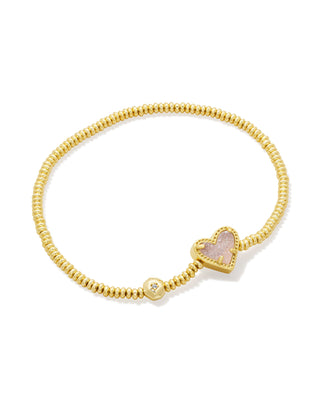 Gold bracelet with a heart-shaped pink charm on a white background
