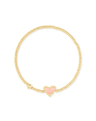 Gold bracelet with a pink heart charm on a white background