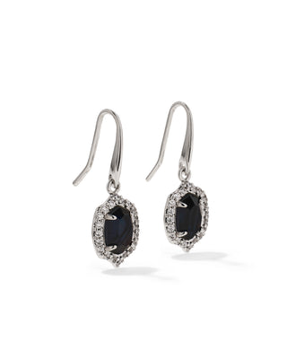 A pair of silver drop earrings featuring oval dark blue gemstones surrounded by small clear pavé stones, set against a plain white background.