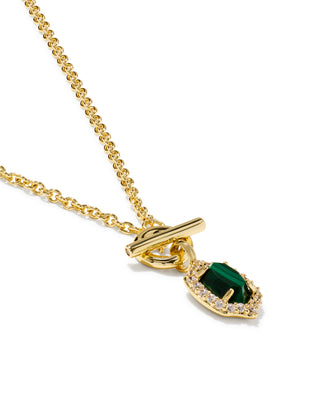 A gold chain necklace with a toggle clasp and a teardrop-shaped pendant featuring a green stone surrounded by small clear stones, shown on a white background.