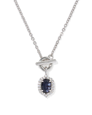 A silver-tone toggle clasp necklace featuring a teardrop-shaped dark blue sapphire gemstone surrounded by a halo of small clear stones, shown on a clean white background.