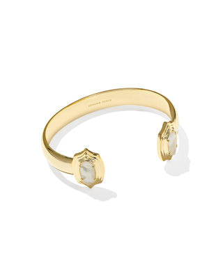 A gold cuff bracelet by KENDRA SCOTT, featuring two open ends set with textured white shell inlays, photographed on a clean white background with soft shadows.