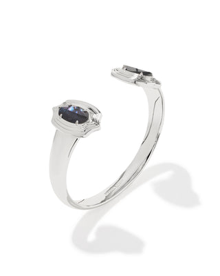 A polished silver-toned open cuff ring featuring a central cushion-cut dark blue sapphire gemstone, displayed on a clean white background with a soft shadow.