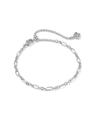 A silver-toned chain anklet featuring elongated oval links, a ball chain extender, a lobster clasp, and a small flower charm, displayed on a clean white background.
