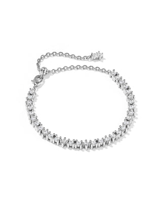 A silver-toned tennis bracelet featuring a row of small clear stones in a prong setting, with an adjustable link chain and clasp, shown on a plain white background.