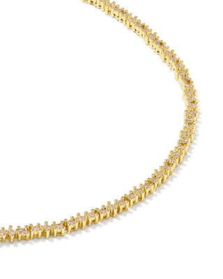 A close-up of a yellow gold tennis necklace with small clear stones set in a repeating curb link design, photographed on a clean white background.