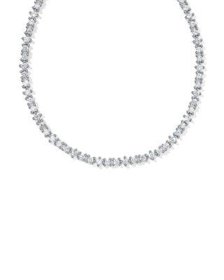 A delicate diamond tennis necklace in a silver-toned setting, arranged in a curved line against a solid white background.