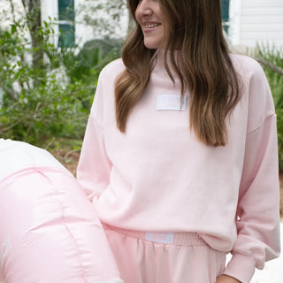 Person wearing a pink sweatshirt with a brand logo outdoors