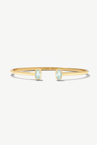 Gold bracelet with light blue gemstones on a white background