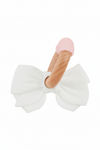 White silicone bow teether with wooden handle and pink top on a white background